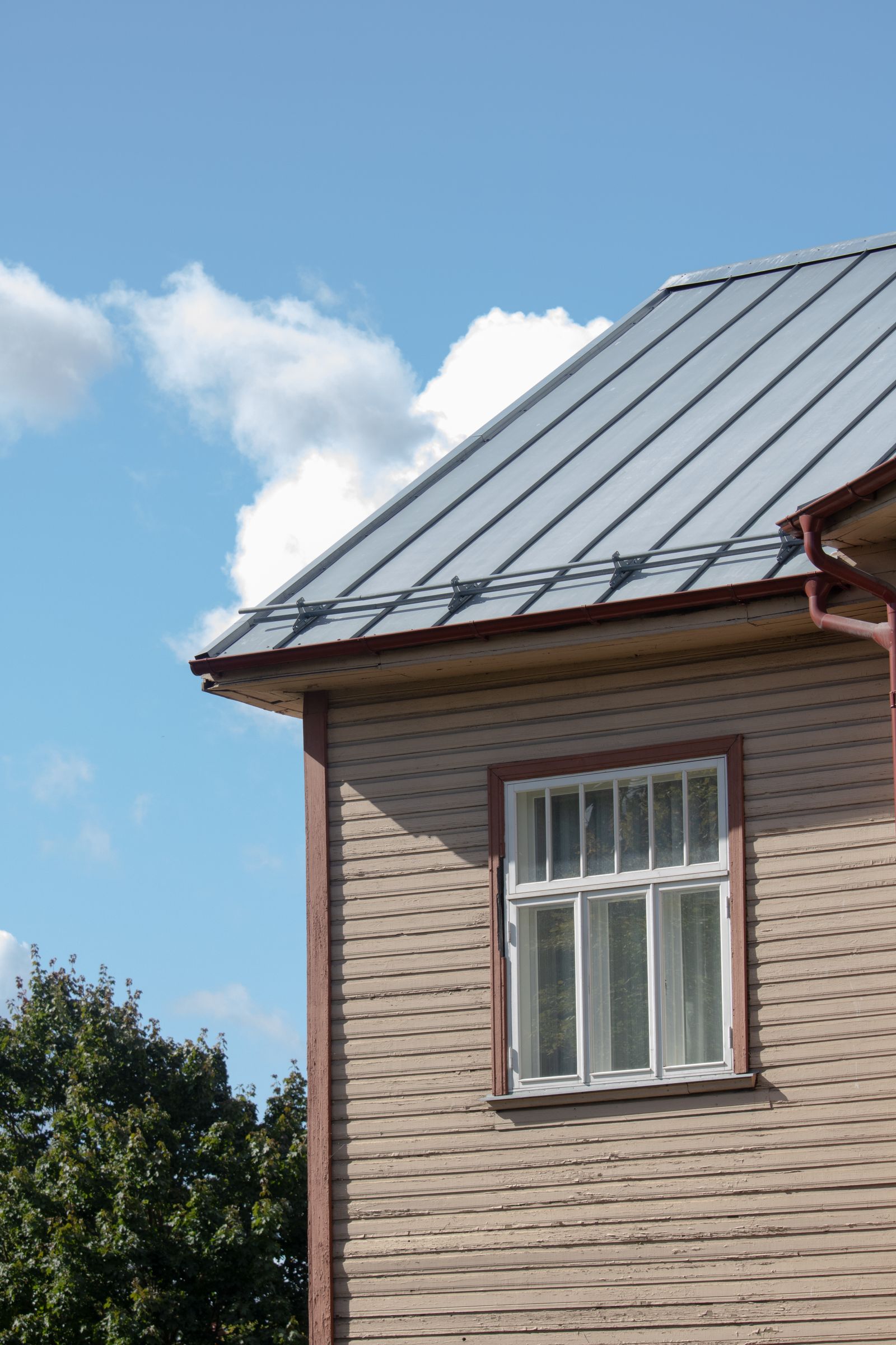 A standing seam metal roof on a house against a clear sky